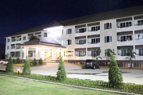 a large white building with a parking lot at night at Siamtara Palace Hotel in Maha Sarakham
