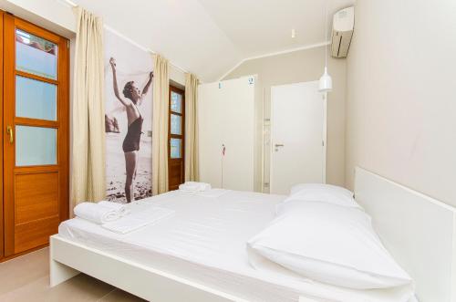 a white bedroom with a bed and a poster of a woman at Hostel Dvor in Split