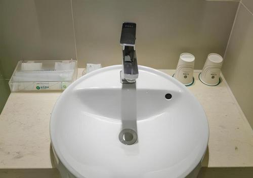 a white toilet with a faucet in a bathroom at City Comfort Inn Wuhan Jiefang Avenue Xinrong Light Rail Station in Wuhan