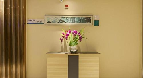a vase of flowers on a table in a room at City Comfort Inn Wuhan Jiefang Avenue Xinrong Light Rail Station in Wuhan