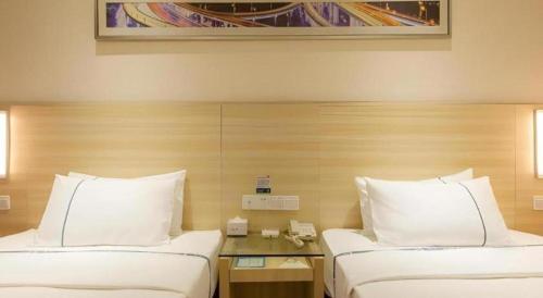 two beds in a hotel room with white pillows at City Comfort Inn Wuhan Jiefang Avenue Xinrong Light Rail Station in Wuhan