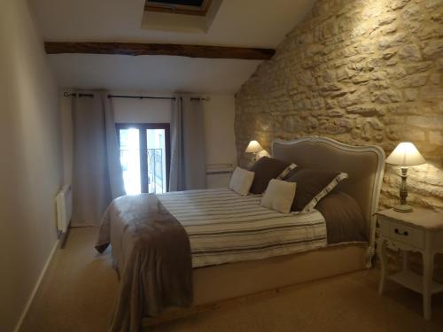 een slaapkamer met een bed en een stenen muur bij The Mews in Puligny-Montrachet