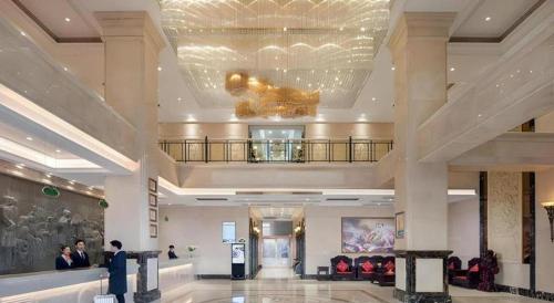 a lobby of a hotel with people standing in it at Vienna Hotel Zhengzhou Exhibition Center Zhengbian Road in Zhengzhou