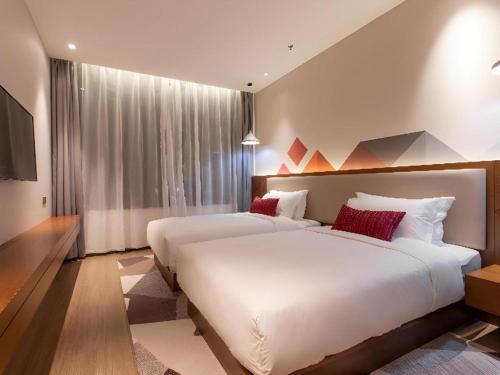a bedroom with two beds and a large window at Borrman Hotel Guilin Railway Station Two Rivers and Four Lakes in Guilin