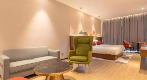 a living room with a green chair and a bed at Borrman Hotel Guilin Railway Station Two Rivers and Four Lakes in Guilin