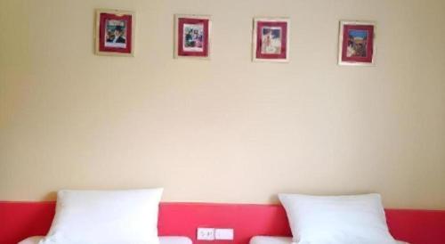 a room with two white pillows and pictures on the wall at C2 Residence Hotel in Lampang
