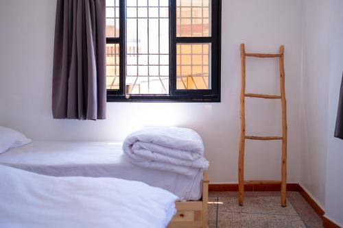 a room with two beds and a ladder and a window at Azurf - Imsouane Surf House in Imsouane