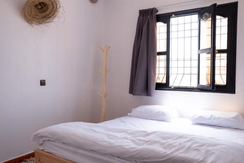 a bedroom with a white bed with a window at Azurf - Imsouane Surf House in Imsouane