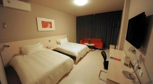 a hotel room with two beds and a television at Jinjiang Inn Shenzhen Airport in Shenzhen