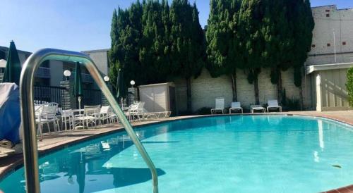 a large swimming pool with blue water and chairs at Pacific Motor Inn in San Jose