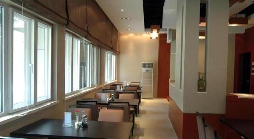 a dining room with tables and chairs and windows at Jinjiang Inn Jiaxing South Lake in Jiaxing