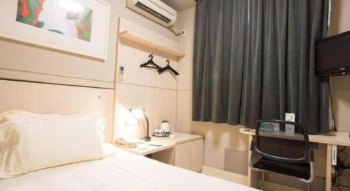 a bedroom with a bed with a chair and a desk at Jinjiang Inn Jiaxing South Lake in Jiaxing