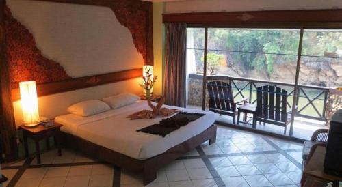 a bedroom with a bed with a view of a balcony at River Kwai Village Hotel in Ban Kaeng Raboet