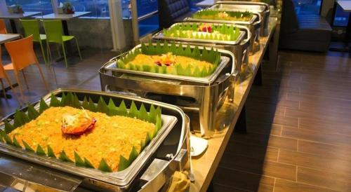a row of trays of food in a cafeteria at Hermes Palace Hotel Medan in Medan