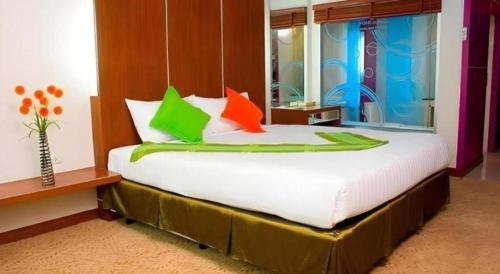 a large bed with colorful pillows in a room at V-One Hotel Korat in Nakhon Ratchasima