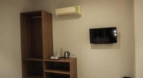 a room with a wall with a tv and a book shelf at Garuda Hotel Pontianak in Pontianak