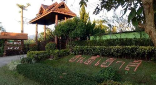 a house with a garden with a sign in the grass at Indie House @ Maerim in Chiang Mai