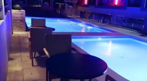 a swimming pool with a table and chairs in front of it at MO2 Westown Hotel San Juan in Bacolod