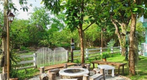 a garden with a bench and a table and a fence at Charisma Resort in Ratchaburi