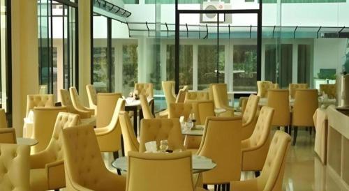 a room filled with chairs and tables and windows at Aramis Hotel in Nakhon Sawan