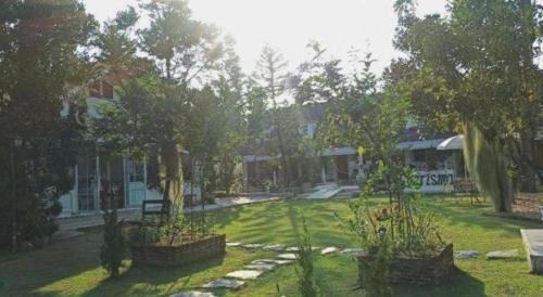 a yard of a house with trees and grass at Charisma Resort in Ratchaburi