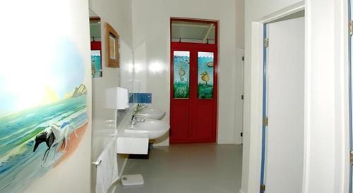 a bathroom with a red door and a sink at Stables Lodge Backpackers in Napier