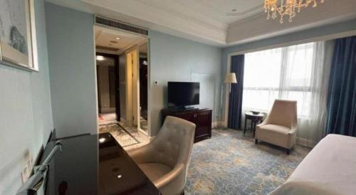 a hotel room with a television and a bedroom at Yuncheng Jianguo Hotel in Yuncheng