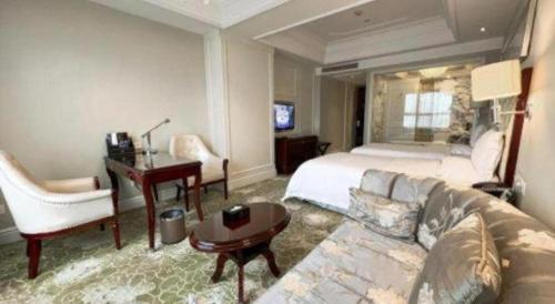 a hotel room with a couch and a bed and a desk at Yuncheng Jianguo Hotel in Yuncheng