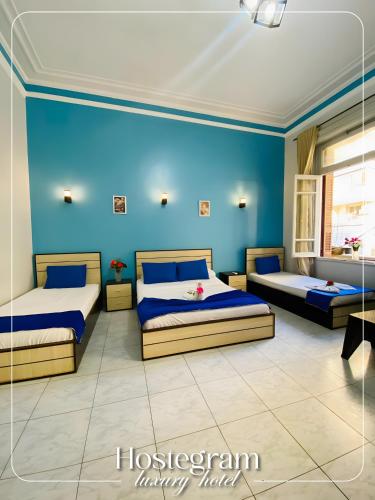 Dos camas en una habitación con paredes azules. en Host Hotel, en El Cairo