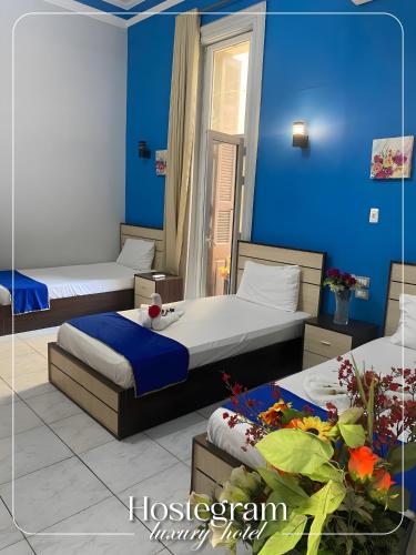 Dos camas en una habitación con paredes azules. en Host Hotel, en El Cairo