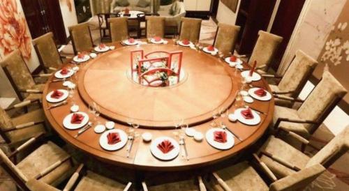 a large wooden table with plates of food on it at Dongwu New Century Grand Hotel Huzhou in Huzhou