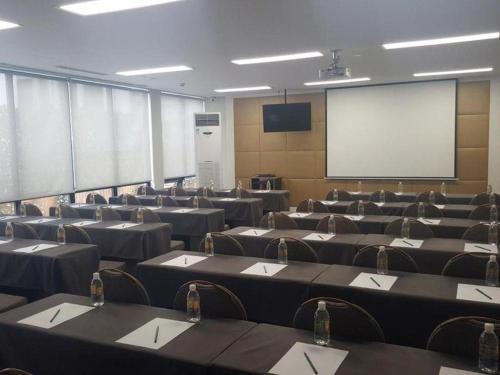 a conference room with tables and chairs and a screen at Jinjiang Metropolo Hotel Classiq Shanghai Off Bund in Shanghai