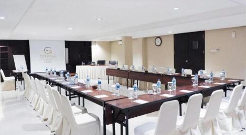 a long table with white chairs and bottles of water on it at Grage Hotel Cirebon in Cirebon
