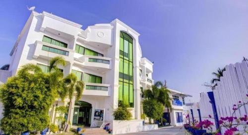 a white building with green windows and palm trees at Vitalis White Sands in Vigan