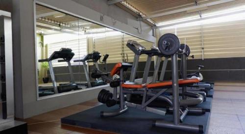 a gym with several tread machines and a mirror at Grage Hotel Cirebon in Cirebon