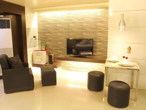 a living room with black chairs and a flat screen tv at One Serenata Hotel General Trias in Silang
