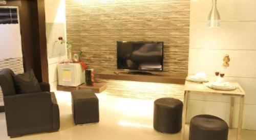 a living room with a flat screen tv and chairs at One Serenata Hotel General Trias in Silang