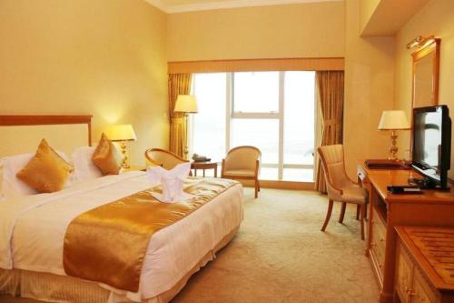 a hotel room with a bed and a television at Zhuhai Dehan Hotel in Zhuhai