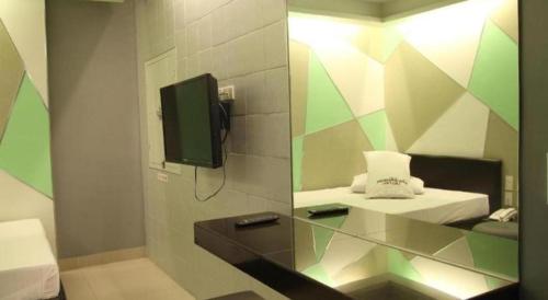 a bathroom with a sink and a tv on a wall at One Serenata Hotel General Trias in Silang