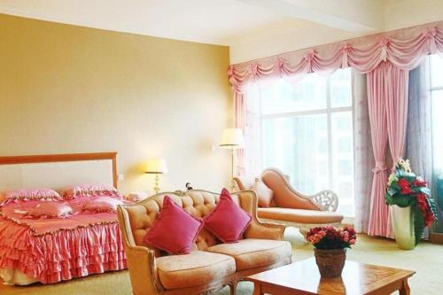 a bedroom with a bed and a couch and a table at Zhuhai Dehan Hotel in Zhuhai