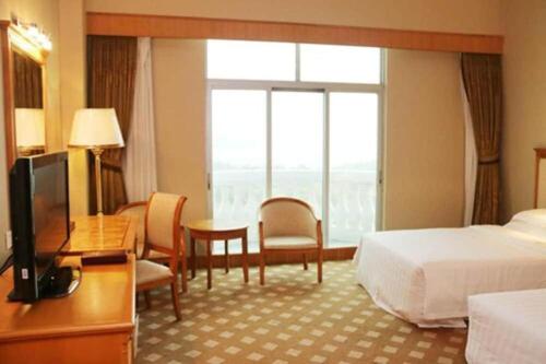 a hotel room with a bed and a desk and a television at Zhuhai Dehan Hotel in Zhuhai