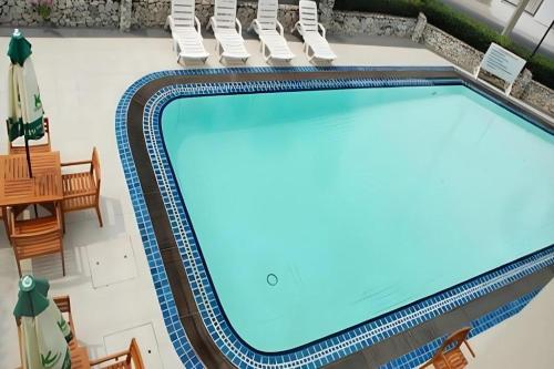 a large swimming pool with chairs and a table at Bangsaen Villa Hotel in Si Racha