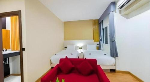 a room with two beds and a red couch at GT Residence Hotel in Buriram