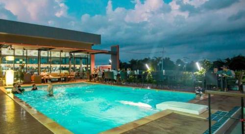 a swimming pool with people in the water at night at GT Residence Hotel in Buriram