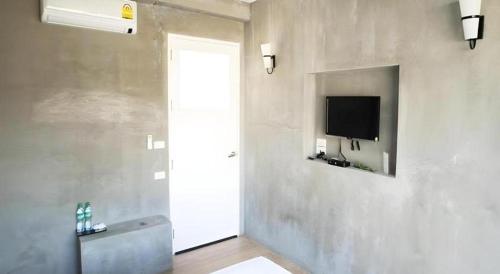 a room with a door and a television on a wall at Ma-Kham Forest Resort in Nakhon Nayok