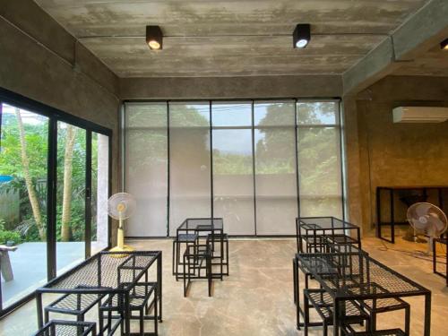 a room with chairs and tables and glass windows at Ma-Kham Forest Resort in Nakhon Nayok