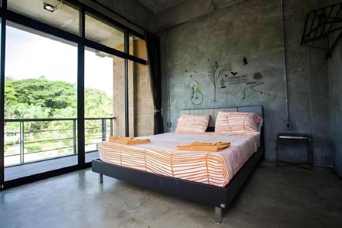 a bedroom with a bed and a large window at Ma-Kham Forest Resort in Nakhon Nayok