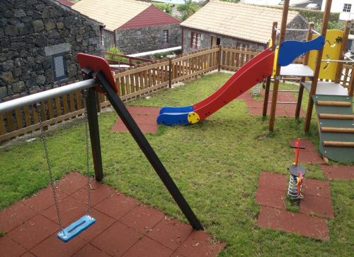 a playground with a slide and a swing at Aldeia das Adegas in São Roque do Pico