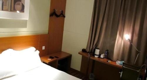 a bedroom with a bed and a desk with a lamp at Jinjiang Inn Style Shenyang The Palace Huaiyuan Gate in Shenyang