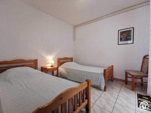 a bedroom with two beds and a chair and a lamp at Grenache rdc in Fosse